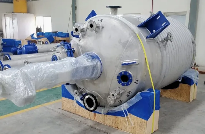 A large stainless steel high-pressure reactor placed on a wooden pallet with agitator assembly and motor gearbox