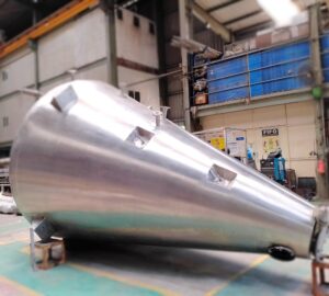 Side view of a large Nauta dryer with inspection ports and support legs in the fabrication workshop