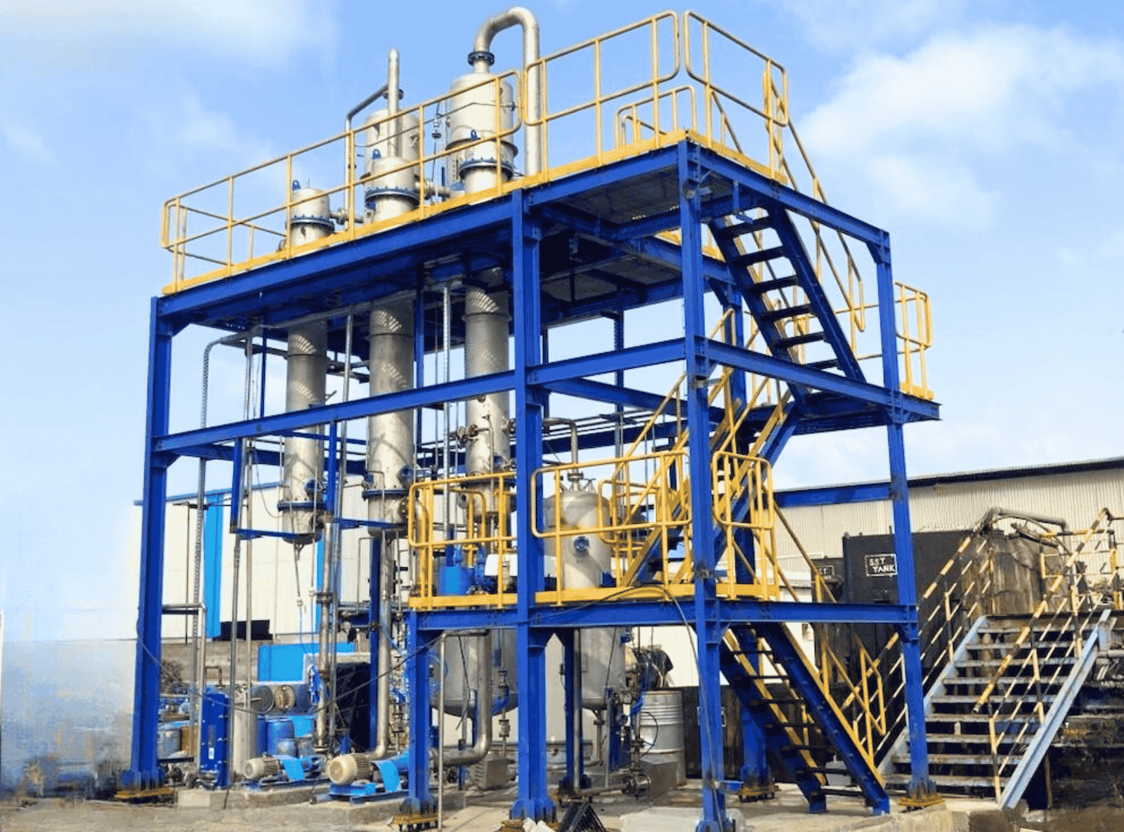 MEE Plant for industrial wastewater treatment featuring a blue and yellow structure, stainless steel evaporator columns, and piping